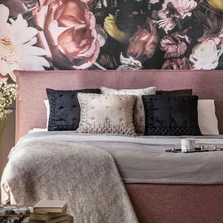 anpassungsfähig - Rosa und grauen Bett mit Kissen in gemusterten Schlafzimmer Innenraum mit Blumen und Lampe. Echtes Foto - Stock-Fotografie